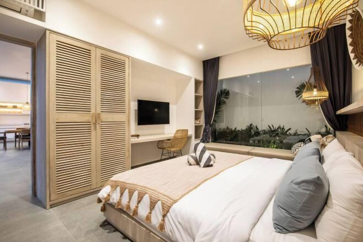 Een moderne slaapkamer met een bed, een televisie, een kledingkast en uitzicht op de omgeving.
