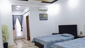 A bedroom with two beds, a potted plant, a framed picture on the wall, and an air conditioning unit. - RU YI HOTEL(SMC-PRIVATE) LIMITED (Islamabad)