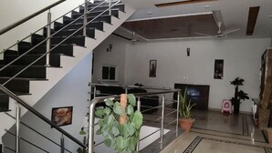A staircase with metal railings, a potted plant, a television, and a speaker in a modern interior. - RU YI HOTEL(SMC-PRIVATE) LIMITED (Islamabad)