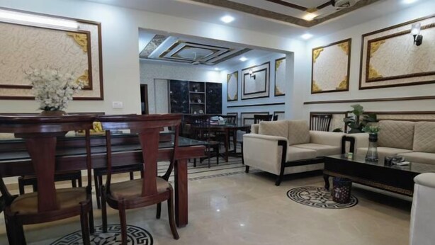A spacious living room with a dining area, featuring a sofa set, a coffee table, and a decorative vase. - RU YI HOTEL(SMC-PRIVATE) LIMITED (Islamabad)