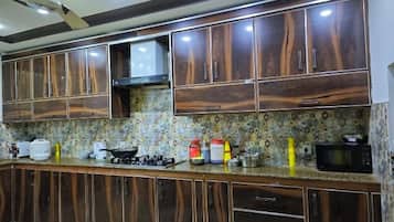 Una cocina con armarios de madera oscura, salpicadero con diseño y varios electrodomésticos, incluyendo un microondas y una estufa a gas.