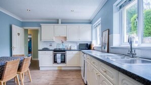 A kitchen with white cabinets, a black countertop, and a window with a view of greenery.