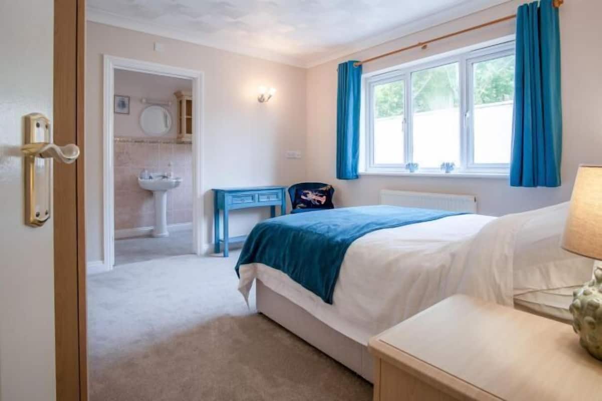 A bedroom with a bed, bedside table, and a window with curtains.