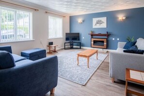 Un salon moderne avec un canapé, une table basse, un téléviseur et une cheminée.