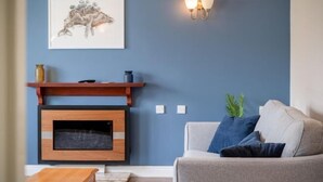 A living room with a fireplace, a sofa, a coffee table, and a wall-mounted light fixture.