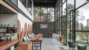 A modern interior with a bar area, seating, and large windows offering views of the outdoors. - Misty Valley Doichang (Mae Suai)