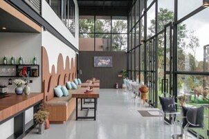 Un intérieur moderne avec un espace bar, des sièges et de grandes fenêtres offrant une vue sur l’extérieur.