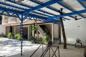 An outdoor covered area with a staircase, potted plants, and a bicycle. - Zinnia (Maafushi)