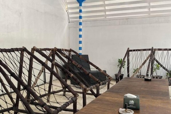 A wooden table with a tissue box and a remote control, surrounded by rope barriers and a chair.