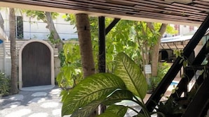 A covered outdoor area with a wooden ceiling, a circular door, and surrounding greenery. - Zinnia (Maafushi)