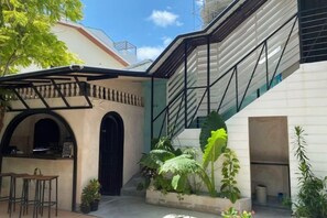 Un pati amb zona d'estar coberta, una escala i plantes en testos.