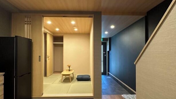 A modern interior with a sliding door leading to a room with tatami mats, a small table, and a sofa. - Kin・ Tengachaya8-14 (Osaka)