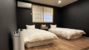 A room with two beds, a small bedside table, an air conditioning unit, and a window with a view. - Kin・ Tengachaya8-14 (Osaka)