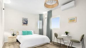 A modern bedroom with a bed, a desk, two chairs, a small table, and a window. - Netanya Beach & Pool Chic Studio (Netanya)