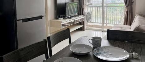 Cocina compacta con refrigerador, microondas y un televisor de pantalla plana sobre un soporte.