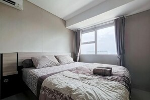 A hotel room with a bed, a window, and a view of the city. - MODERn Trivium Apt 1BR w/ Wi-Fi, Pool & Gym (South Cikarang)