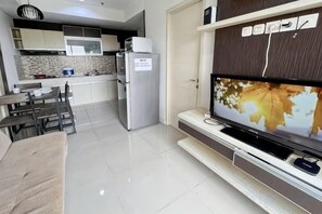 Een moderne keuken met een koelkast, een eettafel en een flatscreen televisie aan de wand.