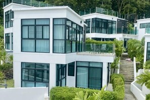 Un immeuble moderne à plusieurs étages, doté de grandes fenêtres, de balcons et d’un escalier menant à un niveau supérieur.