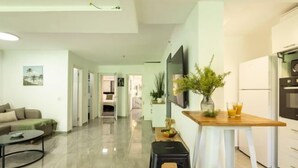 A modern living space with a kitchen, a dining area, and a seating area with a sofa and coffee table. - Bahai Gardens Serenity Apartment (Haifa)