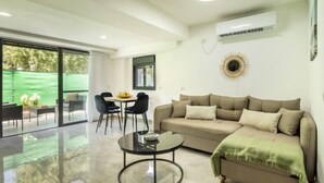 A modern living room with a sofa, a round coffee table, and a dining area with chairs and a table. - Bahai Gardens Serenity Apartment (Haifa)