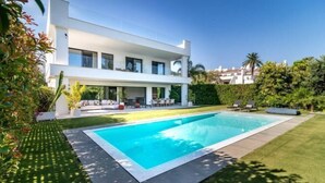 A modern two-story house with a swimming pool, surrounded by well-maintained grass and plants. - All About Villa Gardenias (Marbella)
