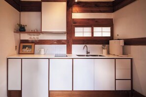 Une cuisine avec des armoires blanches, un plafond en bois et une fenêtre au-dessus de l’évier.