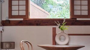 A room with a wooden-framed window, a round table with a white vase, and a modern chair. - [NuileStay] Seoul Gorgeous Hanok - Gyeongbokgung Station(5min) (Seoul)