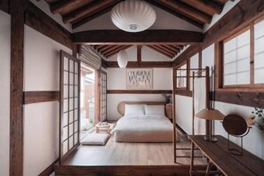 Une pièce de style japonais traditionnel, avec un lit, des poutres en bois, un sol recouvert de tatamis et un paravent shoji.