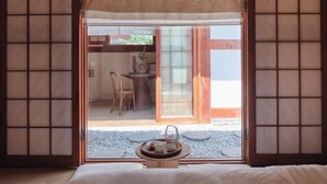 A traditional Japanese-style room with tatami flooring, a low table with a tray of tea and cups, and a sliding door leading to a dining area with a table and chairs. - [NuileStay] Seoul Gorgeous Hanok - Gyeongbokgung Station(5min) (Seoul)