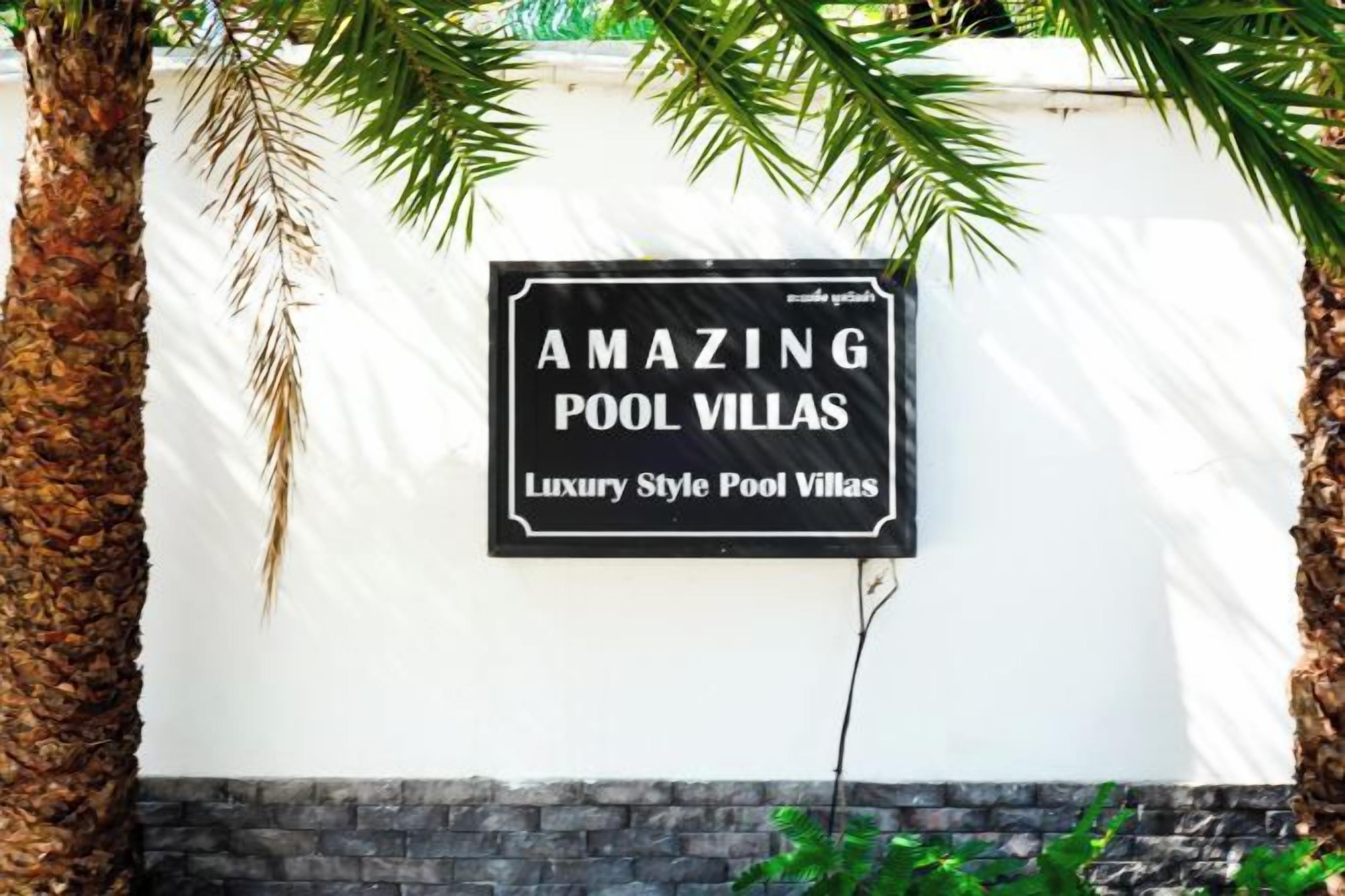 A sign on a white wall advertising 'AMAZING POOL VILLAS' with a black border and white lettering.