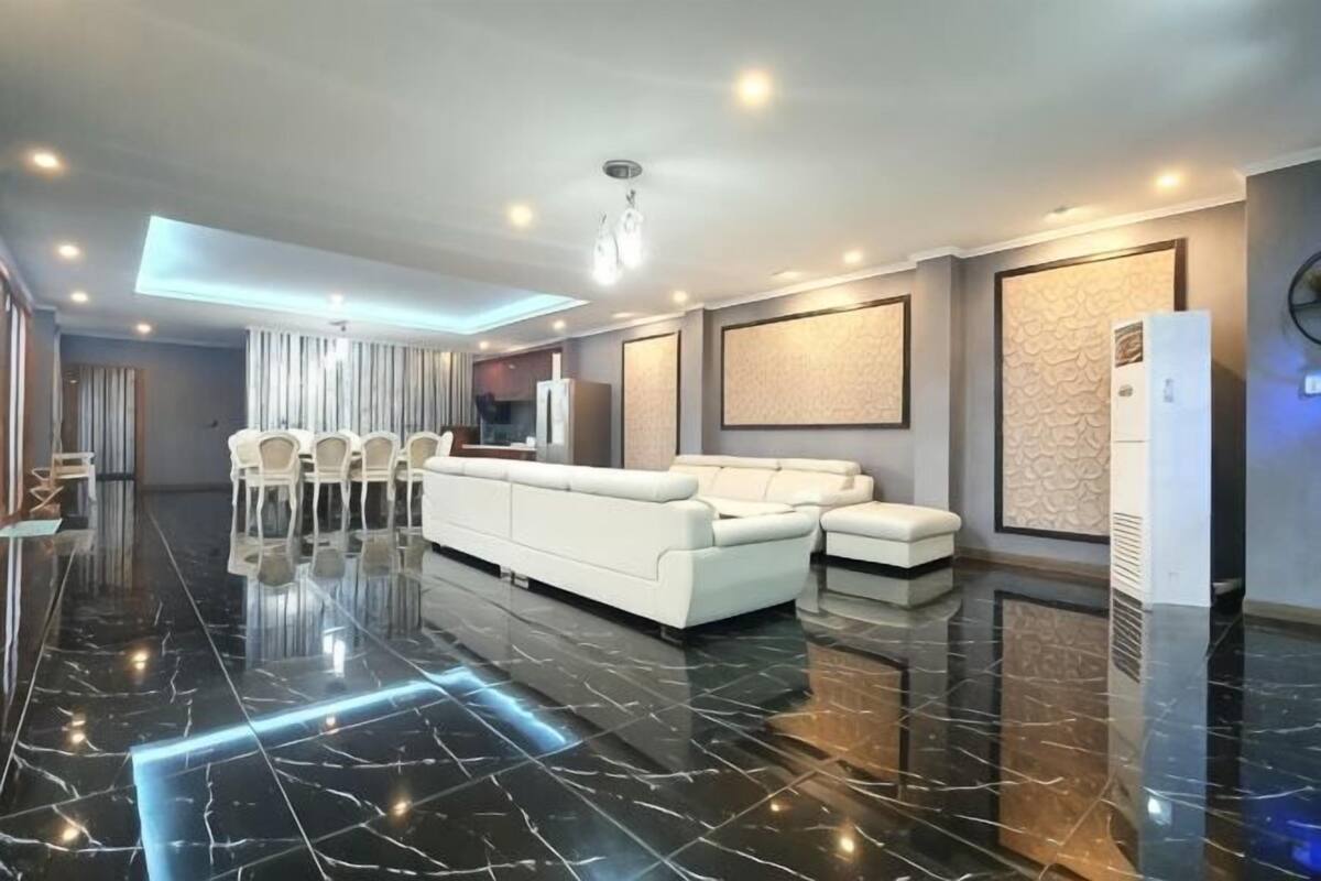A modern living room with a black marble floor, white sofas, and a ceiling light fixture.