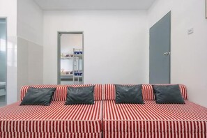 A room with a striped red and white sofa, a grey door, and a visible bathroom in the background. - 28 RESIDENCE-R13 (Sepang)