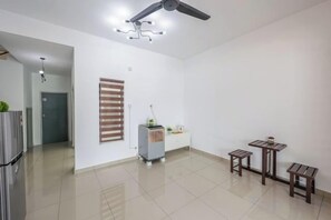Une pièce spacieuse avec un ventilateur de plafond, une petite table et un banc.