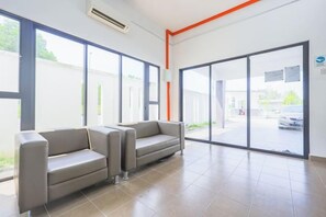 A waiting area with two sofas, large windows, and a view of the outside. - 28 RESIDENCE-R13 (Sepang)