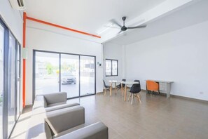 A spacious room with a large sliding glass door, a ceiling fan, a dining area with tables and chairs, and a seating area with sofas. - 28 RESIDENCE-R13 (Sepang)