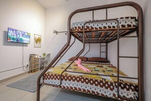 A bunk bed with a patterned bedspread, a desk with a chair, a television, and a wall-mounted picture. - 28 RESIDENCE-R13 (Sepang)