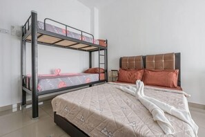 A bunk bed with a lower bunk, a single bed with a quilt, and a nightstand with a lamp. - 28 RESIDENCE-R13 (Sepang)