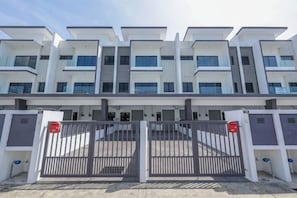 Un immeuble résidentiel à plusieurs étages, doté d’une entrée sécurisée par un portail et d’un toit plat.