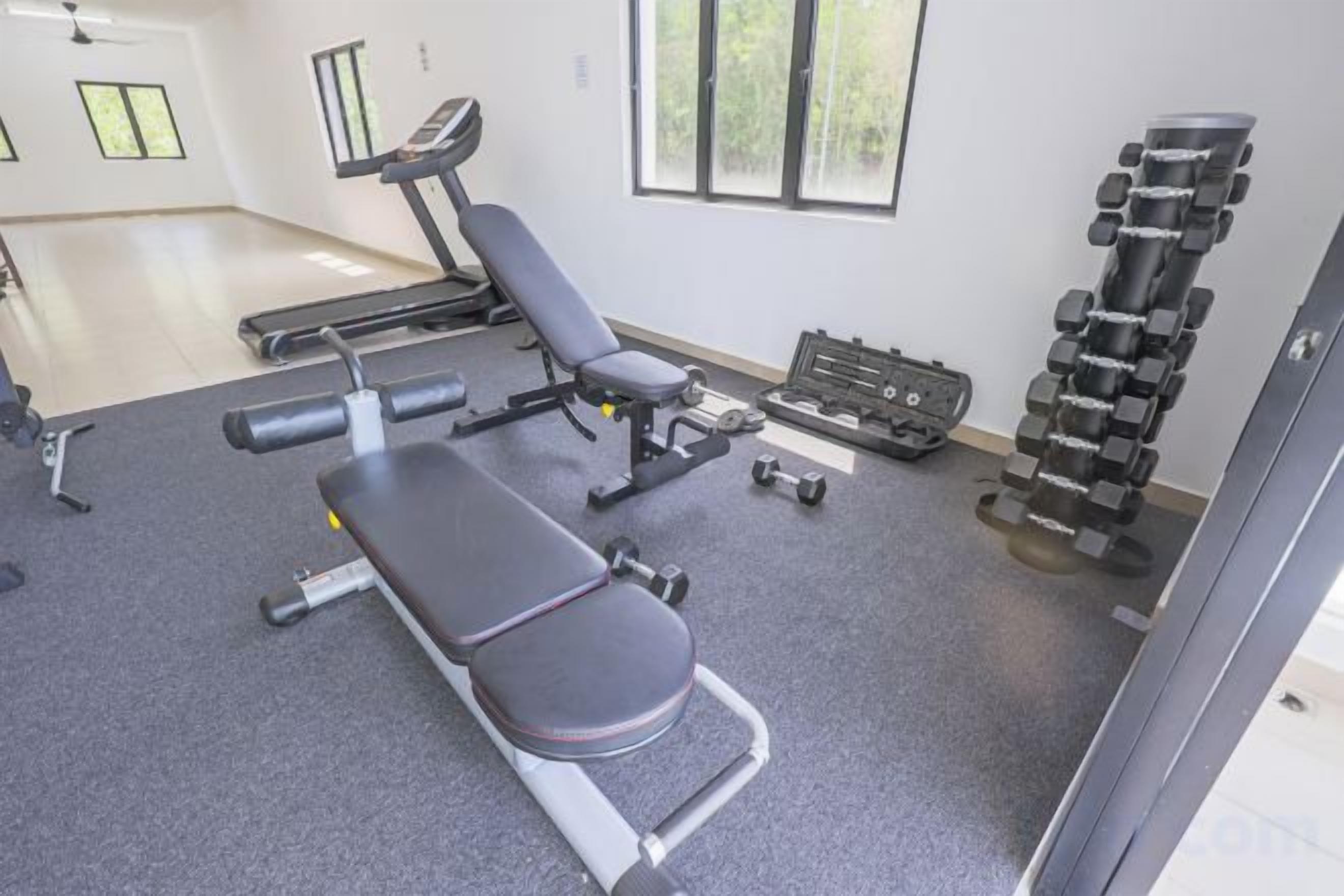 A gym with exercise equipment including a bench, dumbbells, and weight machines.