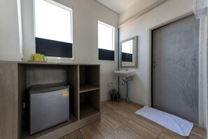 Una habitación pequeña con un refrigerador, un lavamanos, un espejo y una puerta.