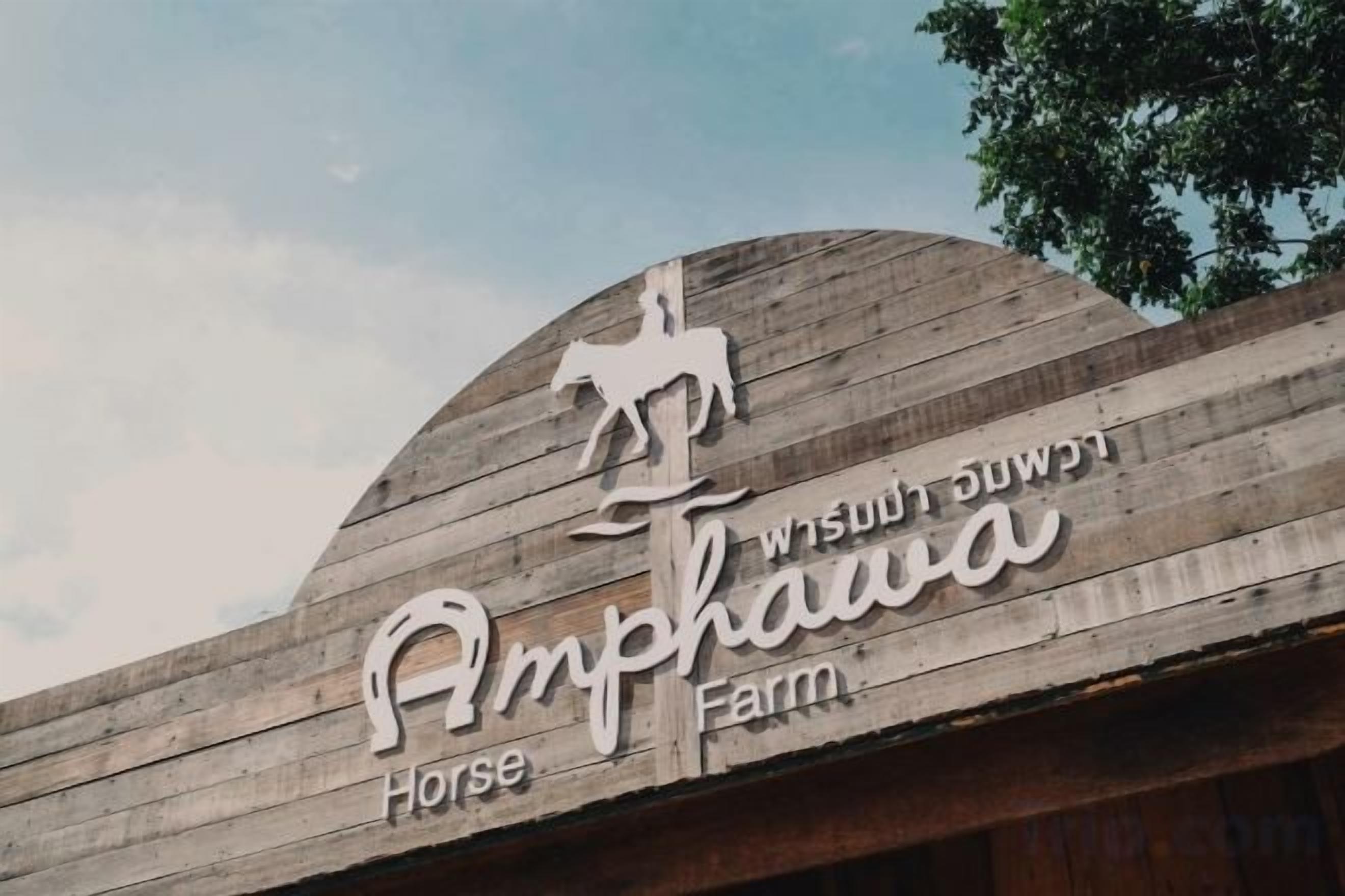 Un letrero de madera con el texto 'Amphawa Horse Farm' y la silueta de un caballo.