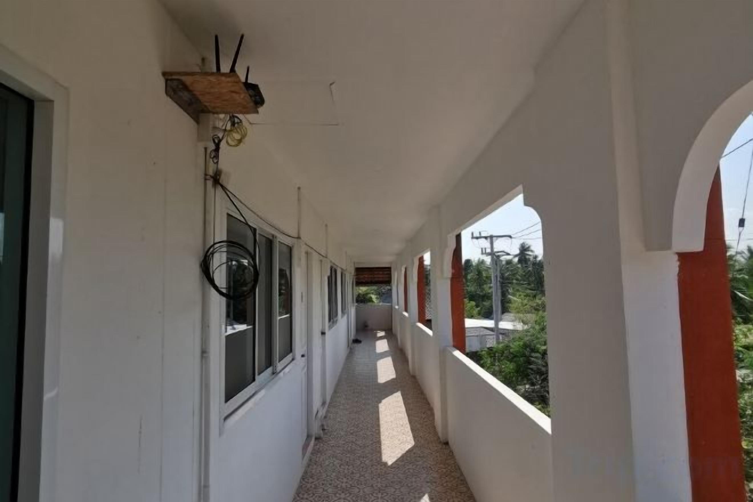 A covered corridor with windows, a wooden shelf, and a view of greenery.