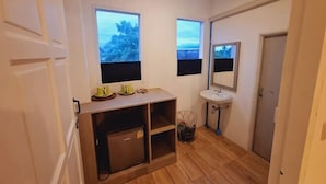 Une petite salle de bain comprenant un lavabo, un miroir et deux fenêtres.