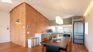Une cuisine moderne avec des murs en bois, un coin repas avec une table et des chaises, et un four encastré.