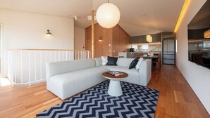 Un salon moderne avec un canapé d’angle gris, une table basse et un tapis à motifs.