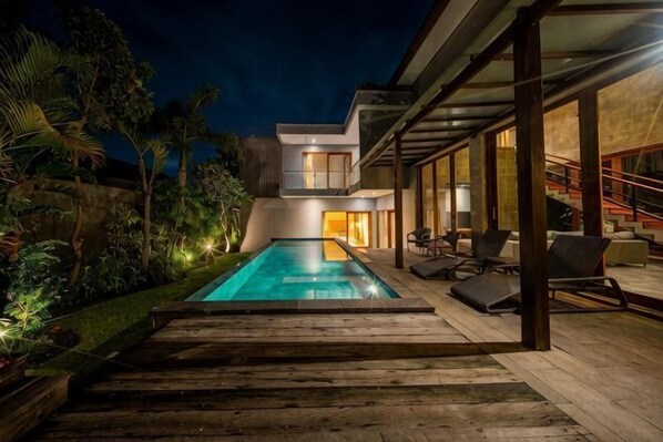 A modern house with a swimming pool, outdoor seating, and a staircase.