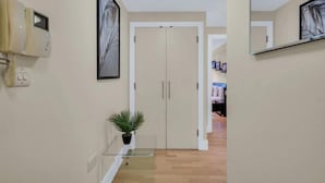 A hallway with a telephone, framed artwork, a potted plant, and a wardrobe.
