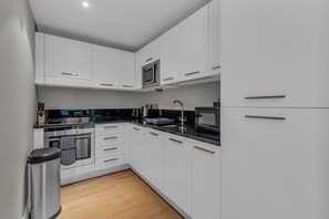 Una cocina moderna con armarios blancos, una estufa de acero inoxidable y un microondas.
