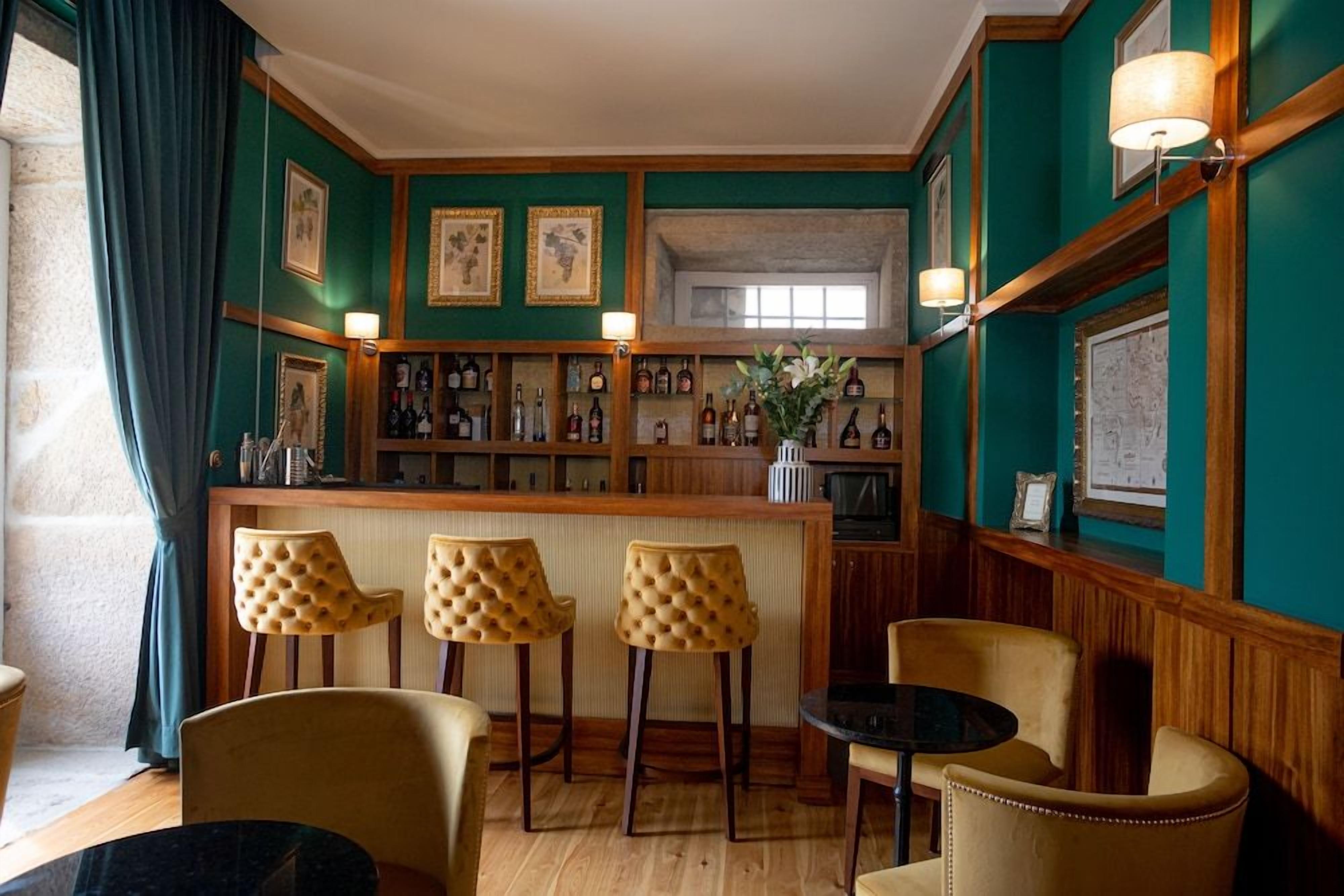 Una zona de bar con mostrador de madera, taburetes y una pequeña mesa redonda.