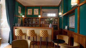 Una zona de bar con mostrador de madera, taburetes y una pequeña mesa redonda.